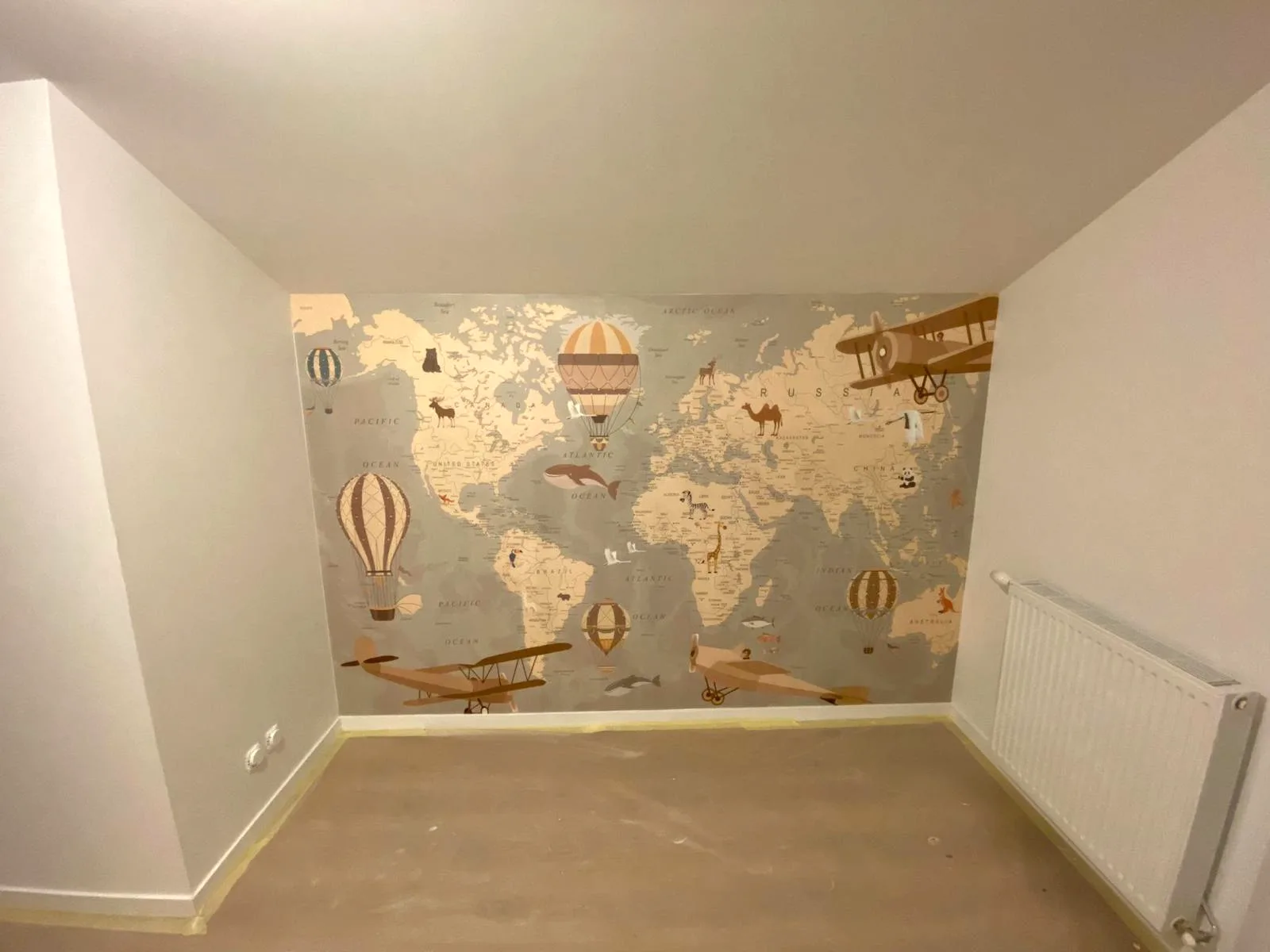 Pose de papier peint carte du monde dans une chambre d'enfant par DOD Peinture.