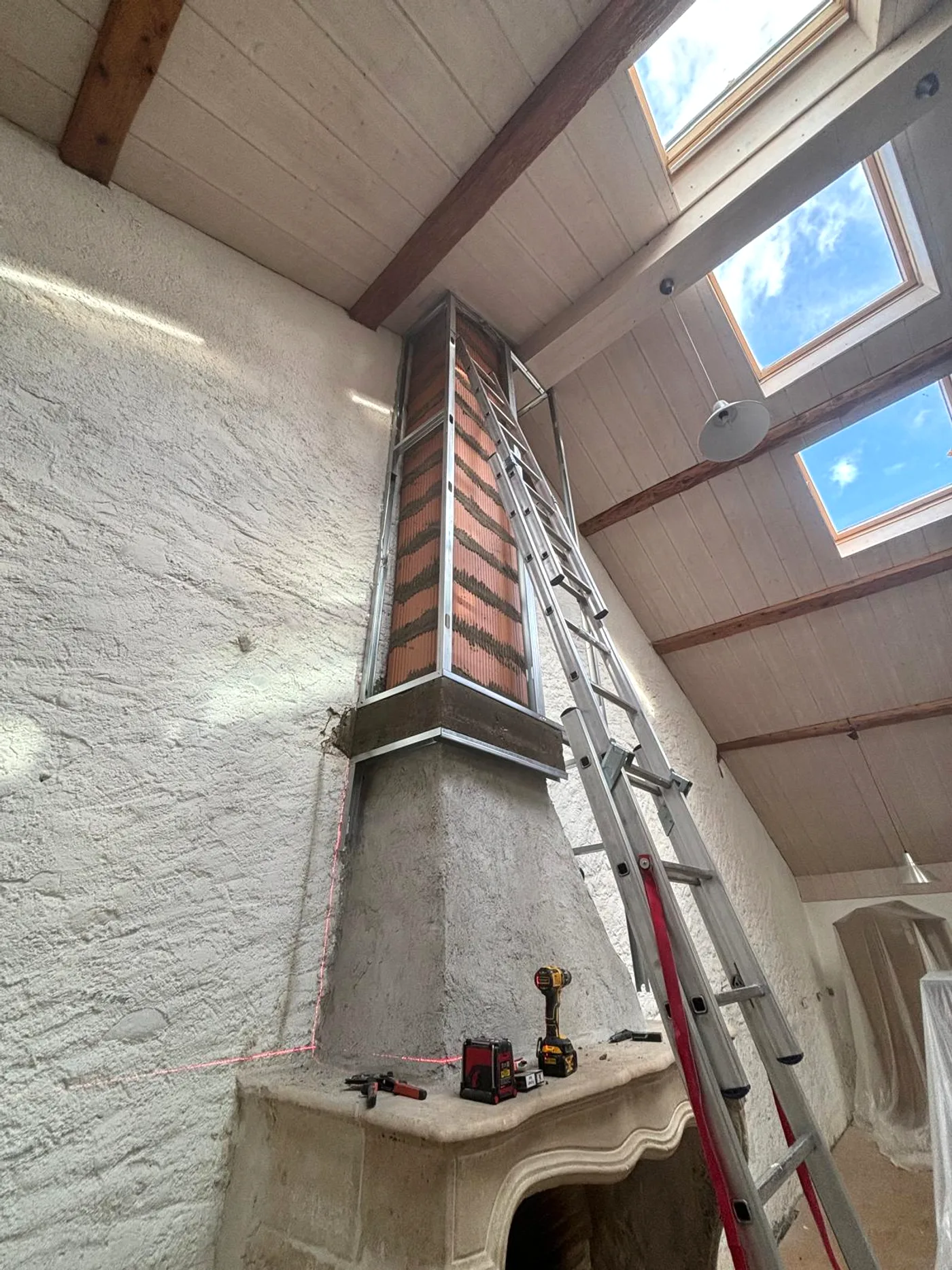Cheminée avant travaux : conduit en brique mis à nu, ossature métallique posée.