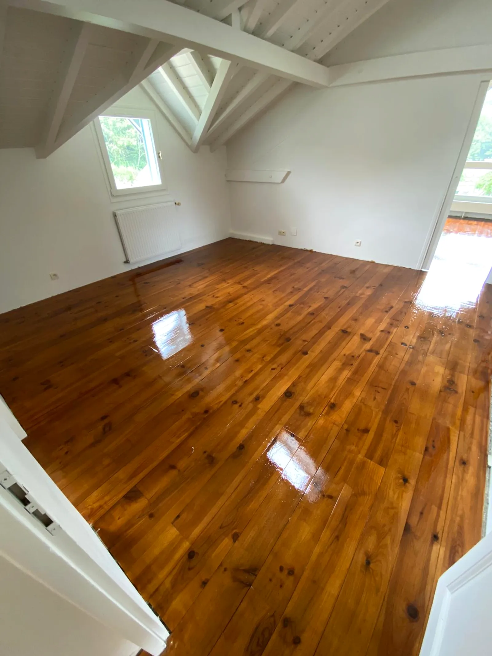 Parquet en bois poncé, teinté et vitrifié par DOD Peinture dans une pièce sous combles.