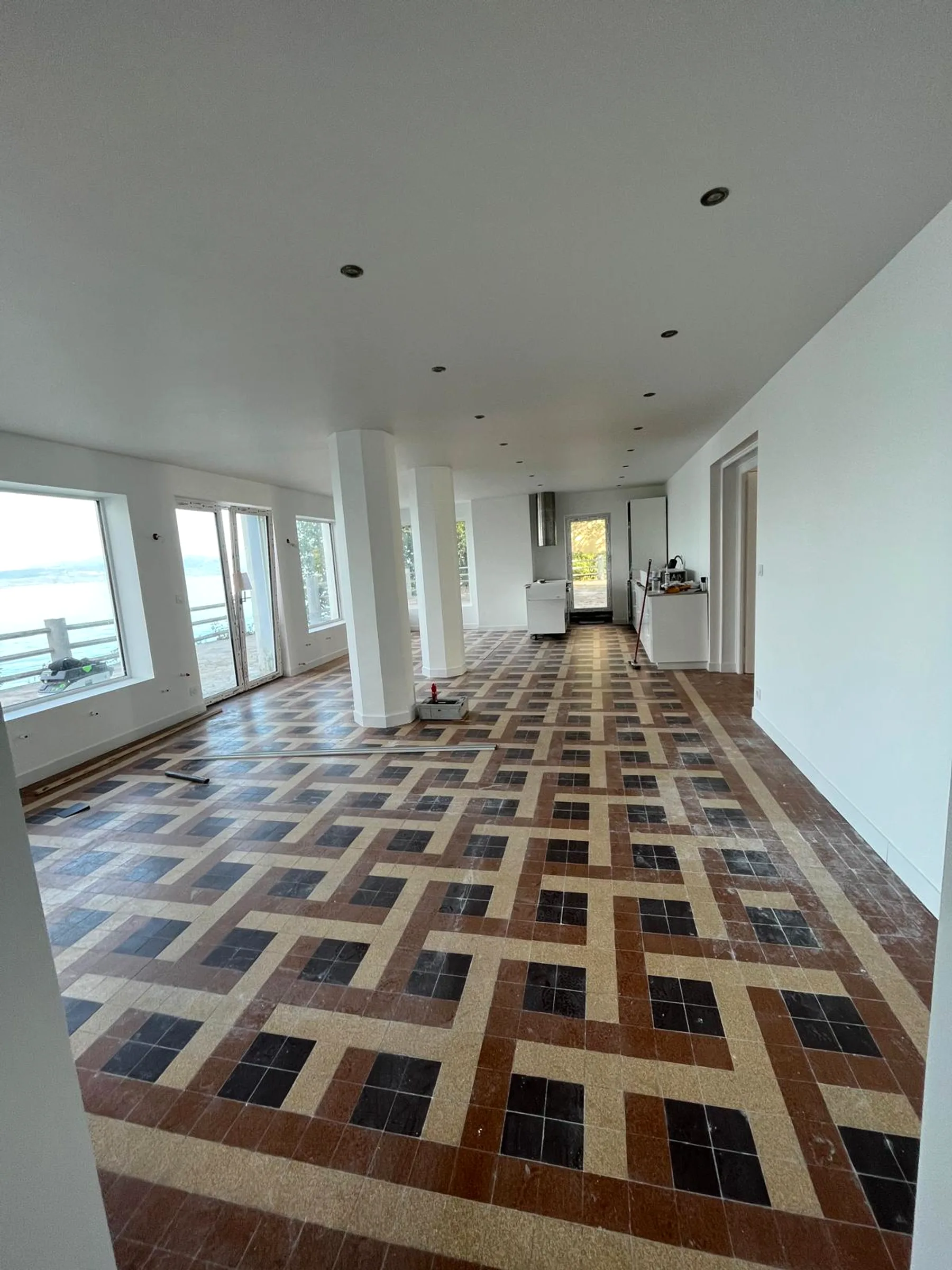 Grand salon rénové par DOD Peinture, murs blancs et carrelage d'époque préservé.